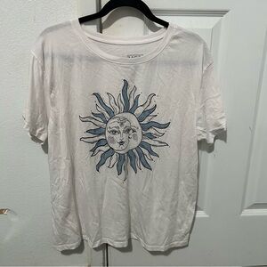 White shirt with blue and black sun and moon print on the front.